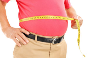 Fat mature man measuring his belly with measurement tape, isolated on white background